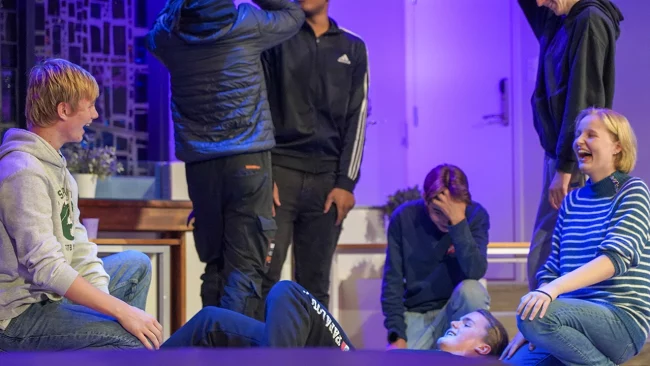 Unge mennesker ler sammen i aulaen